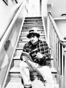 Poet Thom Bakelas sitting on staircase reading a boo